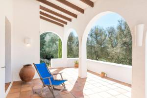 a blue chair in a room with windows at Finca Ses Curtanetas by 3VILLAS in Alaior