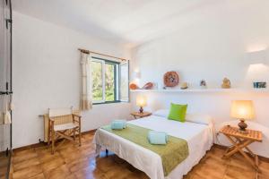 a bedroom with a bed and a chair and a window at Finca Ses Curtanetas by 3VILLAS in Alaior