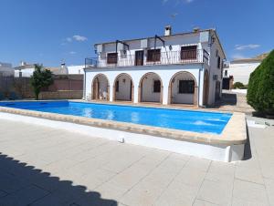a villa with a swimming pool in front of a building at Villa los Solares Casa para grupos in Corcoya
