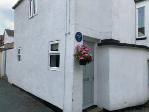 a white house with a flower pot on the door at Artists Cottages Artists Loft near Hornbeam Park Free Parking in Harrogate