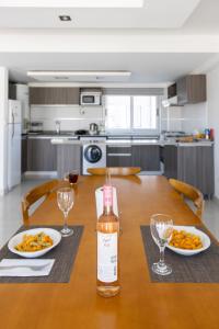 a table with two plates of food and a bottle of wine at HOMEFULL Apartamentos in Salta