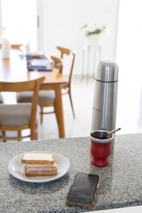 a table with a plate with a sandwich and a cup of coffee at HOMEFULL Apartamentos in Salta