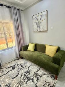 a green couch in a living room with a window at Black-Oak Apartments in Lusaka