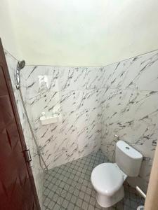 a bathroom with a white toilet and a marble wall at Secretspot Yogyakarta in Yogyakarta +14 photos