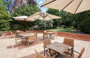 an outdoor patio with tables and chairs and umbrellas at Sercotel Porta Barcelona in Sant Just Desvern