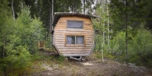 a wooden cabin in the middle of a forest at Rustic Cabin on Off-Grid Homestead in Brattfors