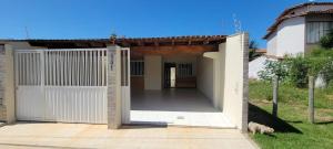 a house with a white gate and a driveway at Casa de praia em Guriri in Guriri