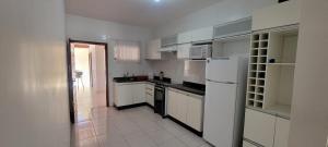 a white kitchen with white appliances and a hallway at Casa de praia em Guriri in Guriri