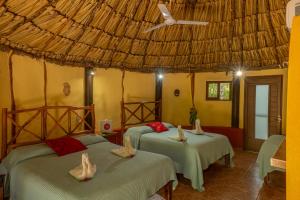 ein Schlafzimmer mit zwei Betten und einem Strohdach in der Unterkunft The Pickled Onion Hotel & Restaurant Uxmal in Santa Elena + 150 Fotos