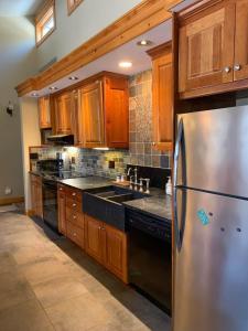 a kitchen with a stainless steel refrigerator and wooden cabinets at Private Lakefront with Dock! in Bethel