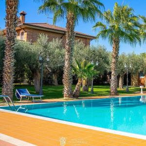 a swimming pool with palm trees in front of a house at Grand Hotel Vigna Nocelli in Lucera