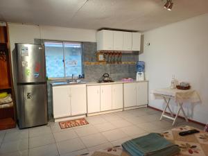 a kitchen with white cabinets and a stainless steel refrigerator at cabañas Te Pito Kura in Hanga Roa