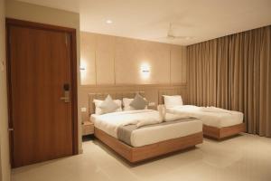 ein Hotelzimmer mit zwei Betten und einer Tür in der Unterkunft Hotel D' Paris in Kozhikode + 33 Fotos