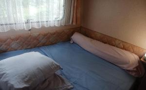 a bed with two pillows in a room with a window at Camping à la Ferme de la Marette in Gluiras
