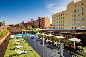 an outdoor patio with chairs and umbrellas and a pool at Sercotel Alcalá 611 in Madrid
