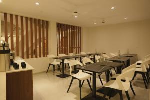 ein Esszimmer mit Tischen und weißen Stühlen in der Unterkunft Hotel D' Paris in Kozhikode