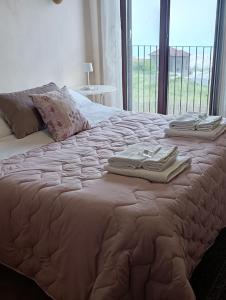 a bed with two folded towels on top of it at Villa Etna Masi' in Milo