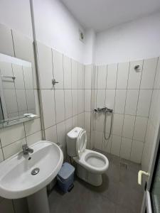 a white bathroom with a toilet and a sink at City Center Hotel in Sarandë