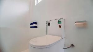 a white bathroom with a toilet and a roll of toilet paper at Anchor House in Ahangama