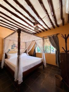 a bedroom with a bed with a canopy at Stay Social Diani - Backpackers & Social Hub in Diani Beach +4 photos