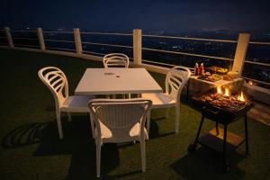 a white table and chairs on a balcony at night at Kanchankanya Hill Resort in Takdāh