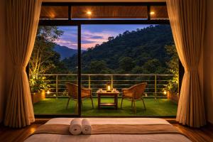 a bedroom with a large window with a table and chairs at Kanchankanya Hill Resort in Takdāh +5 photos