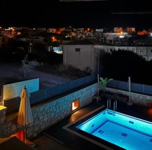 a swimming pool at night with a patio umbrella at Bacbery Butik Otel in Çeşme