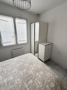 a bedroom with a bed and a refrigerator and windows at Maison 1 chambre in Hyères