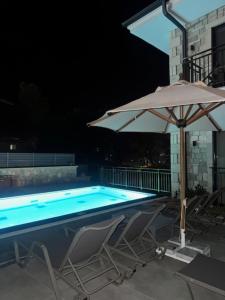 a pool with an umbrella and two chairs and a table and an umbrella at Bacbery Butik Otel in Çeşme