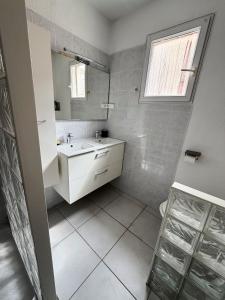 a white bathroom with a sink and a mirror at Maison 1 chambre in Hyères +6 photos
