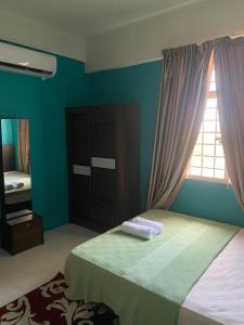 a bedroom with a bed with a dresser and a window at Homestay Plaza in Temerloh +2 photos