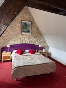 a bedroom with a large bed in a stone wall at Le Château des saveurs in Mello