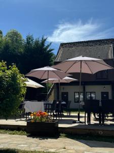 a patio with tables and chairs with umbrellas at Le Château des saveurs in Mello