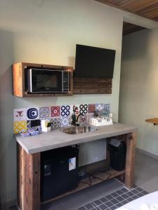 a kitchen counter with a microwave above a sink at Suítes da Sereia in Cananéia