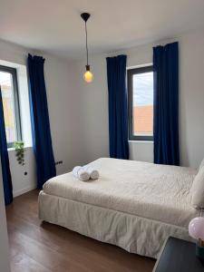 a bedroom with blue curtains and a bed with two towels at Casa Albertina in Mogofores