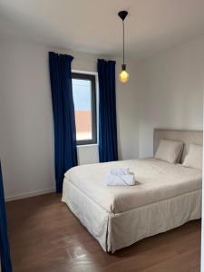 a bedroom with a bed with blue curtains and a window at Casa Albertina in Mogofores