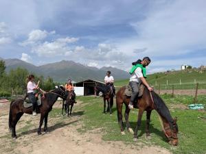 a group of people riding horses in a field at Bugu Too Guest House in Kaindy