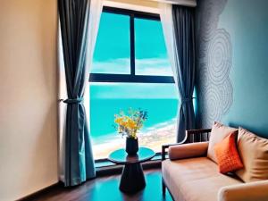 a living room with a couch and a large window at Aura Seaviews Suites in Phan Thiet