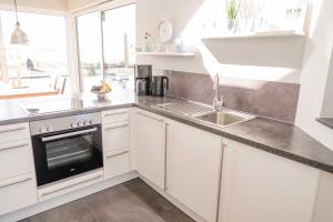 a kitchen with white cabinets and a sink at Ferienhaus Brückenblick 12 a in Fehmarnsund