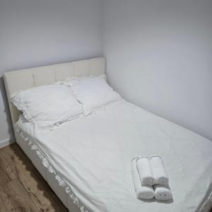 a bed with white sheets and two slippers at Apartament "Agatka" in Hel