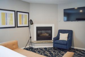 a living room with a fireplace and a blue chair at Creekside Inn Downtown in Cambria