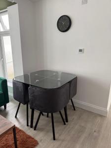 a dining room table with chairs and a clock on the wall at Ground Floor Flat with Courtyard garden in Weston-super-Mare