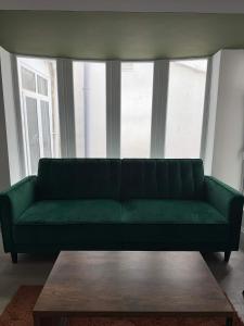 a green couch in a living room with a table at Ground Floor Flat with Courtyard garden in Weston-super-Mare