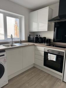 a kitchen with white cabinets and a sink at Ground Floor Flat with Courtyard garden in Weston-super-Mare