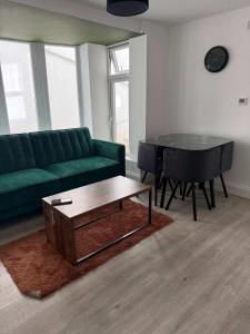 a living room with a green couch and a piano at Ground Floor Flat with Courtyard garden in Weston-super-Mare +12 photos