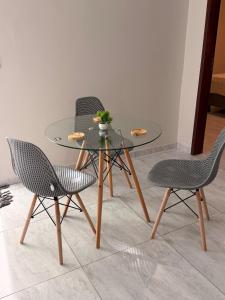 a glass table with three chairs and a table with a plant on it at Comfort Ton House in Juazeiro do Norte