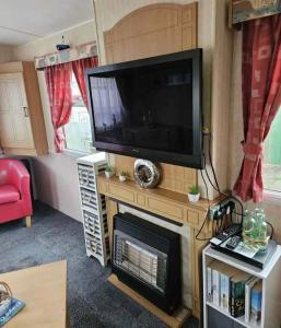 a living room with a flat screen tv and a fireplace at Home from home 2 in Ingoldmells