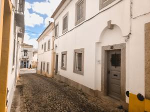 an alley with white buildings and a door at Casa do Mestre By Gt House in Évora