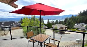 a table and chairs on a balcony with a red umbrella at Lake View Escape! in West Kelowna