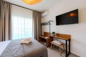 a bedroom with a bed and a desk and a television at Blue Bay Hotel in Skala Potamias